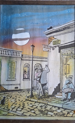 Pareja de tango bailando a las afueras de un café en la calle Carlos Gardel